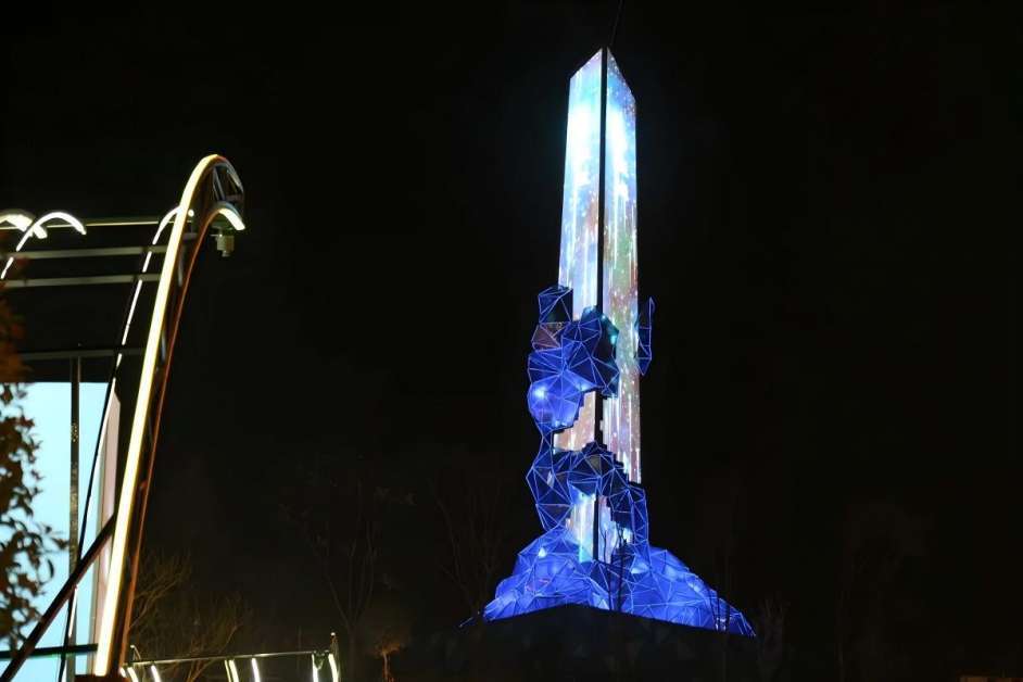 Illuminated tower sculpture with visible polygonal structural frame at night